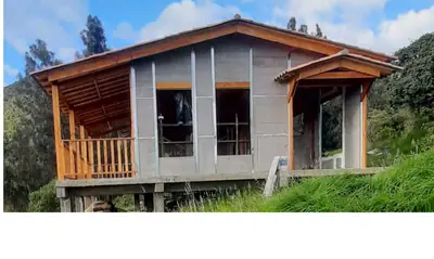 Casa prefabricada de 2 pisos en obra gris con balcón amplio de madera